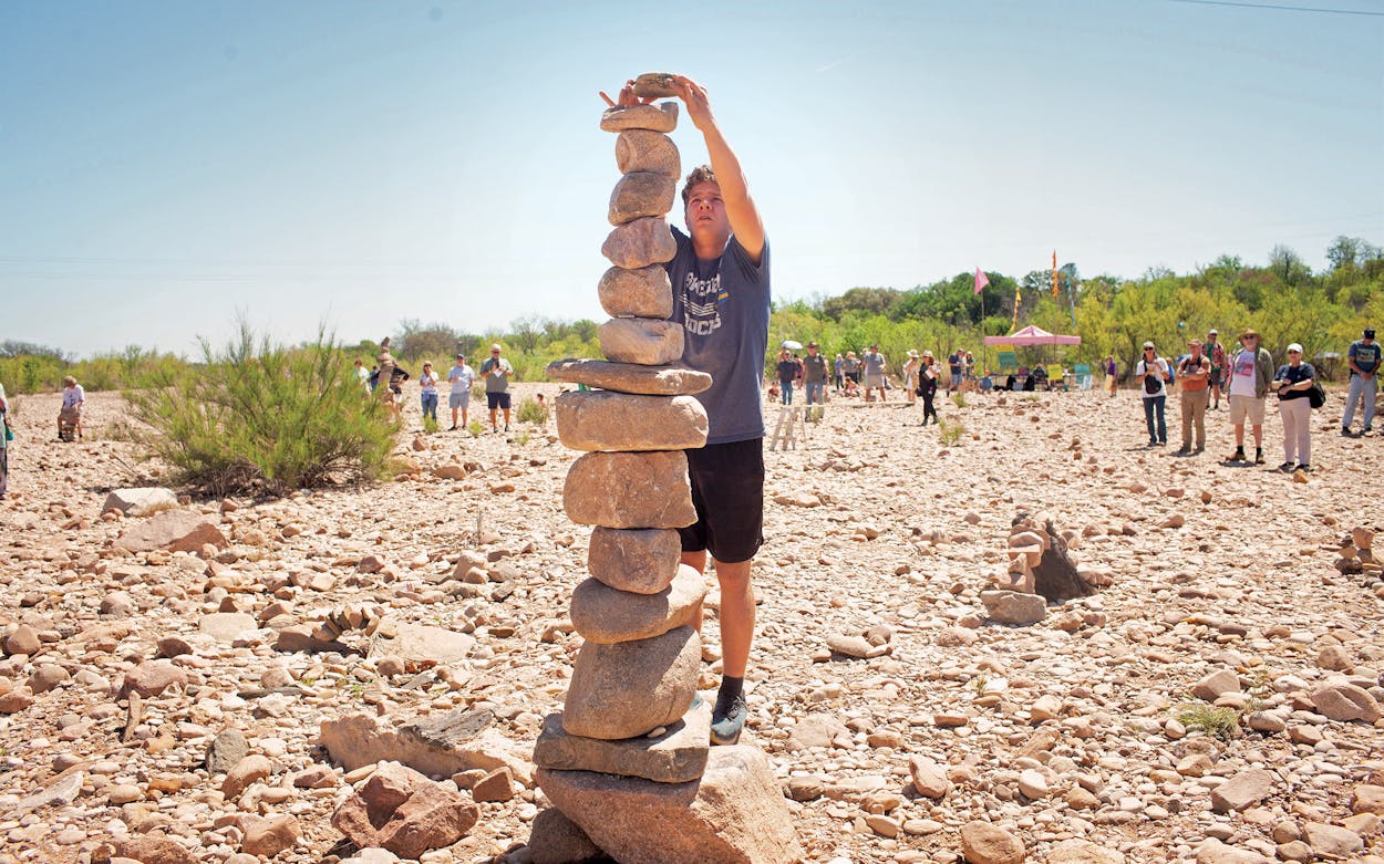 Denton Machuga placing a rock high atop his record-setting 101-inch stack in the individual height competition at the 2023 Llano Earth Art Festival.