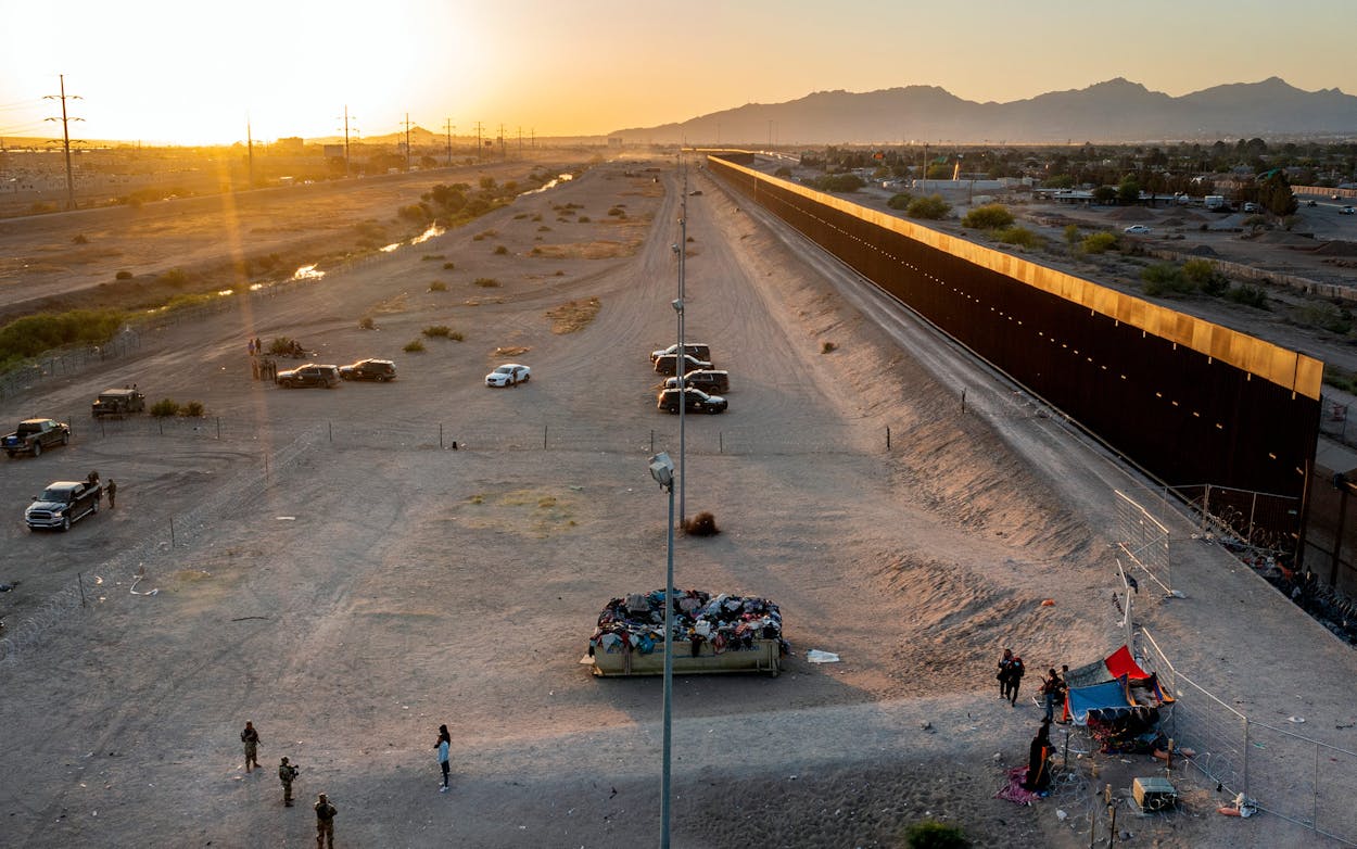 A small group of migrants, bottom right, are pictured while camping outside a gate in the border fence in El Paso, Texas, Friday, May 12, 2023. The border between the U.S. and Mexico was relatively calm Friday, offering few signs of the chaos that had been feared following a rush by worried migrants to enter the U.S. before the end of pandemic-related immigration restrictions.
