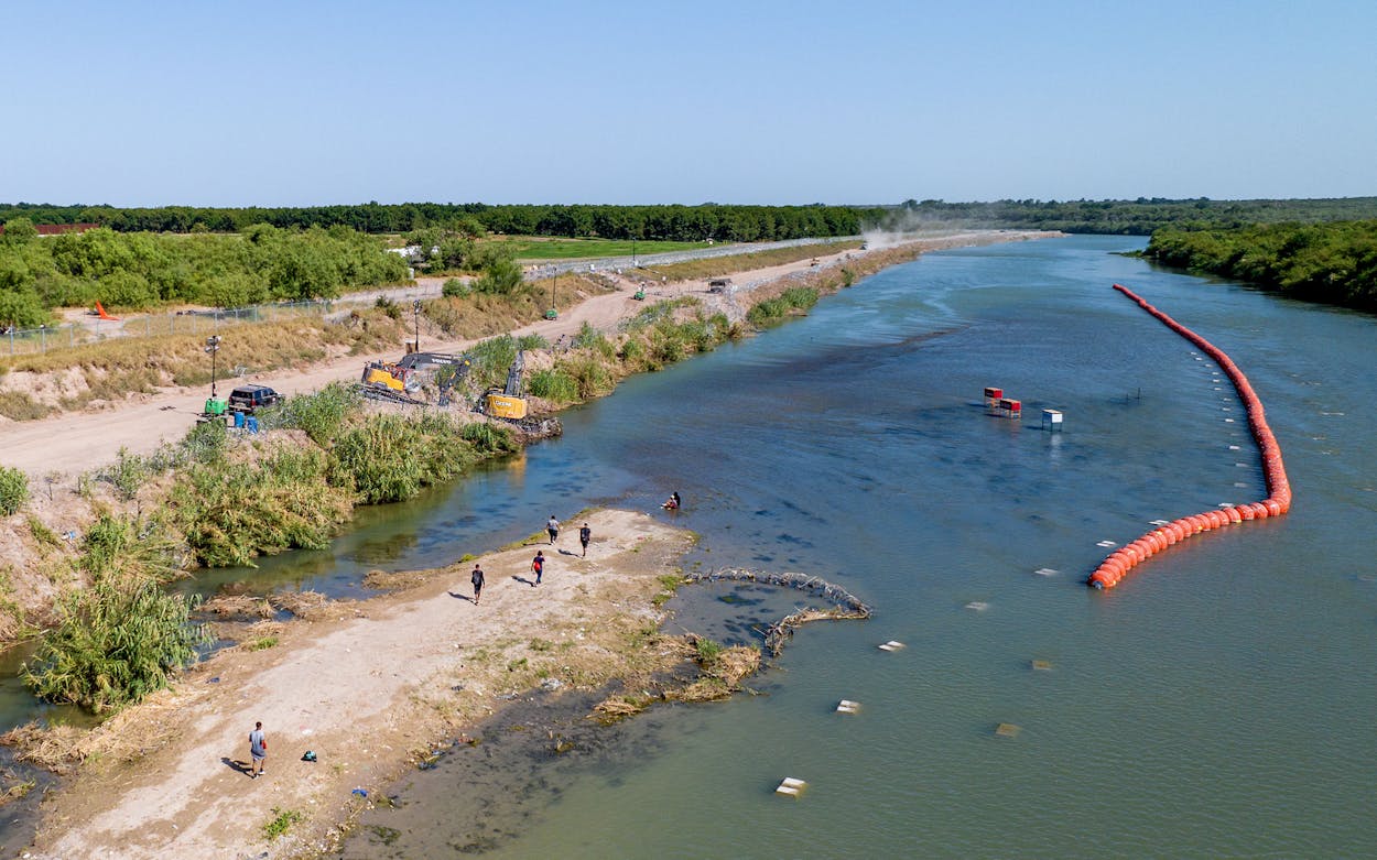 Migrants seeking asylum walk through an island while attempting to cross the Rio Grande into the United States on July 18, 2023, in Eagle Pass, Texas.