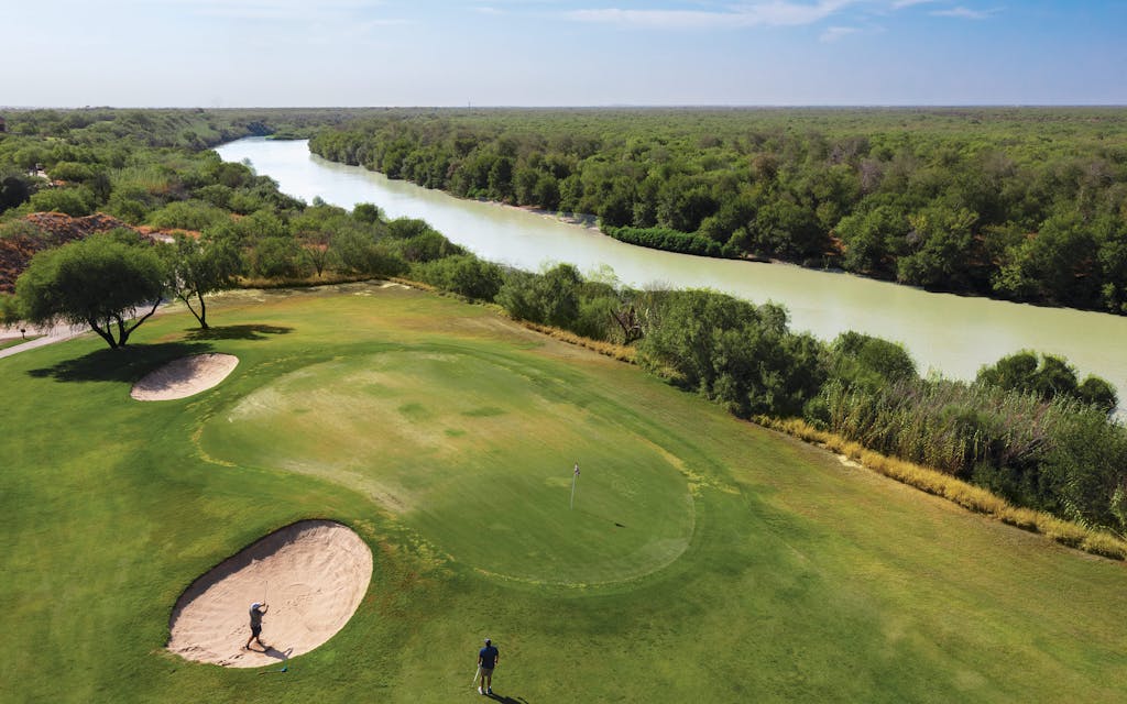 A golfer playing from a sand trap on the ninth hole near the Rio Grande on August 16 at Max A. Mandel, in Laredo.