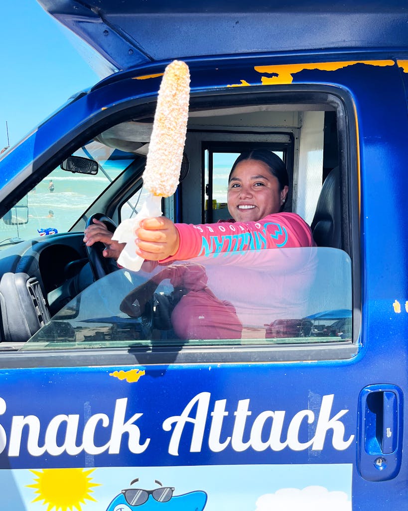 Kelly Hernandez, co-owner of Snack Attack poses with an elote.  
