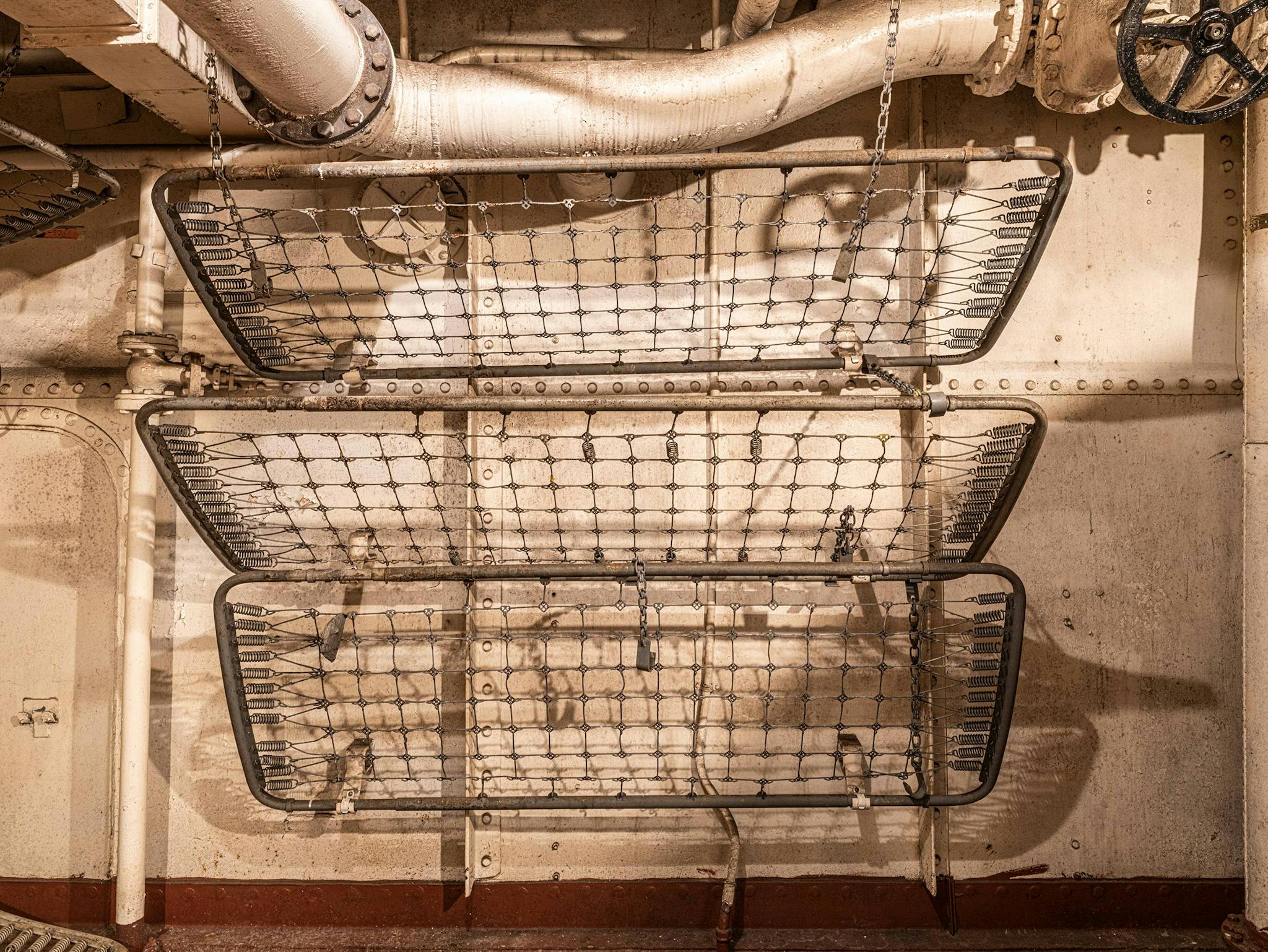 Every sailor had his own place to sleep. Some did so in bunks like these, made of pipe racks on which a thin mattress was thrown, while many dozed in hammocks or cots.