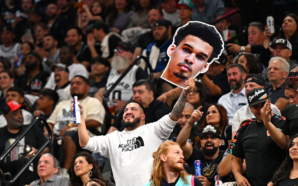 A fan holds a cutout with the face of San Antonio Spurs' French forward-center #01 Victor Wembanyama during the NBA basketball game between the Dallas Mavericks and the San Antonio Spurs at the AT&T Center in San Antonio, Texas on October 25, 2023.