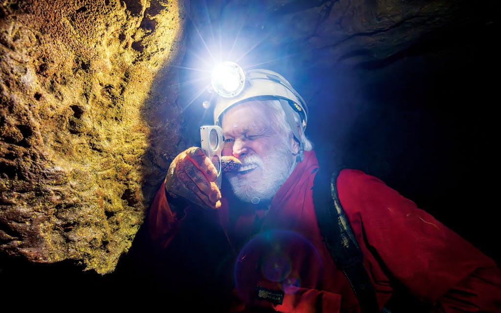 Steele reading a clinometer, a cave-mapping instrument.