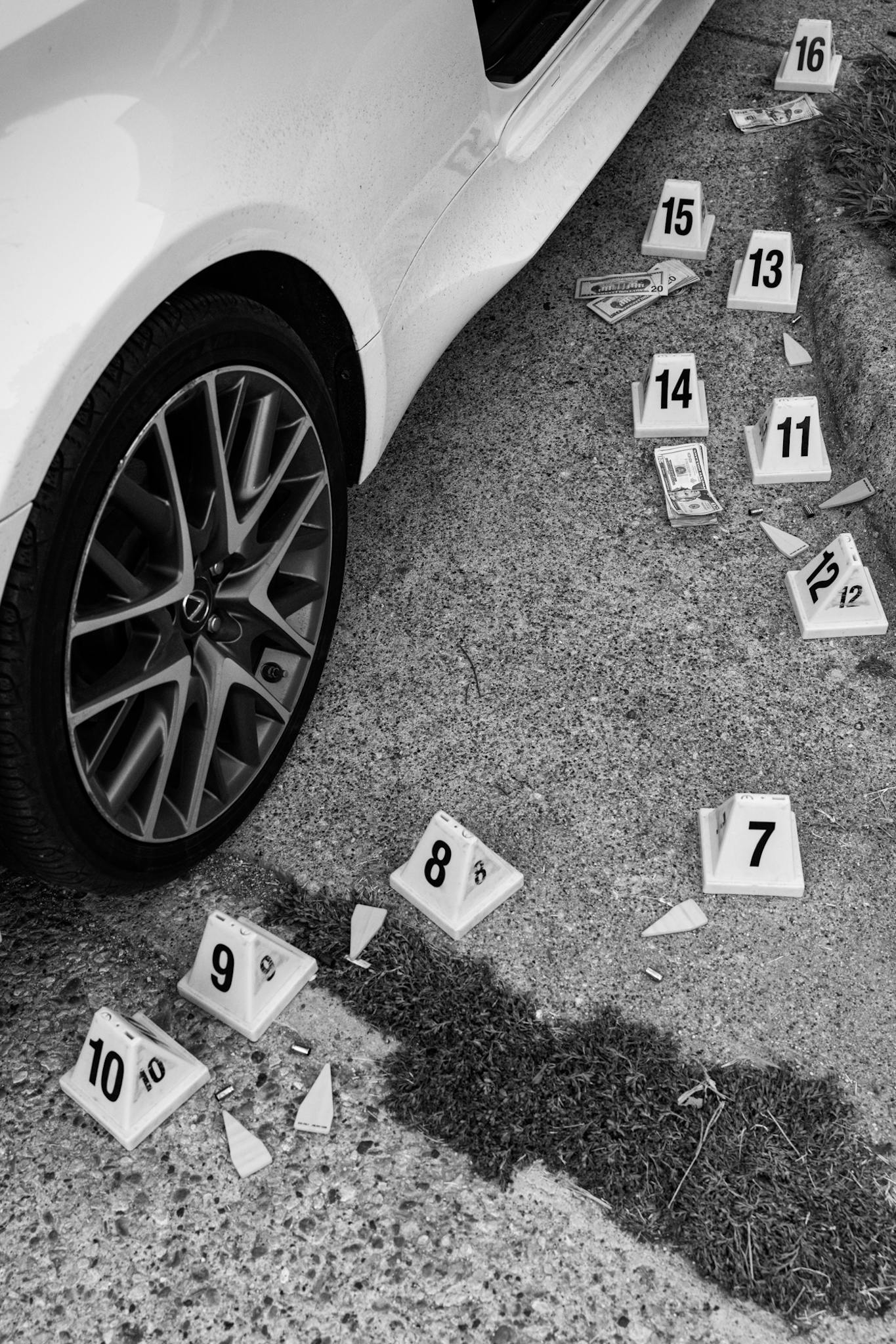 Evidence markers for bullet casings and cash next to a victim’s car.