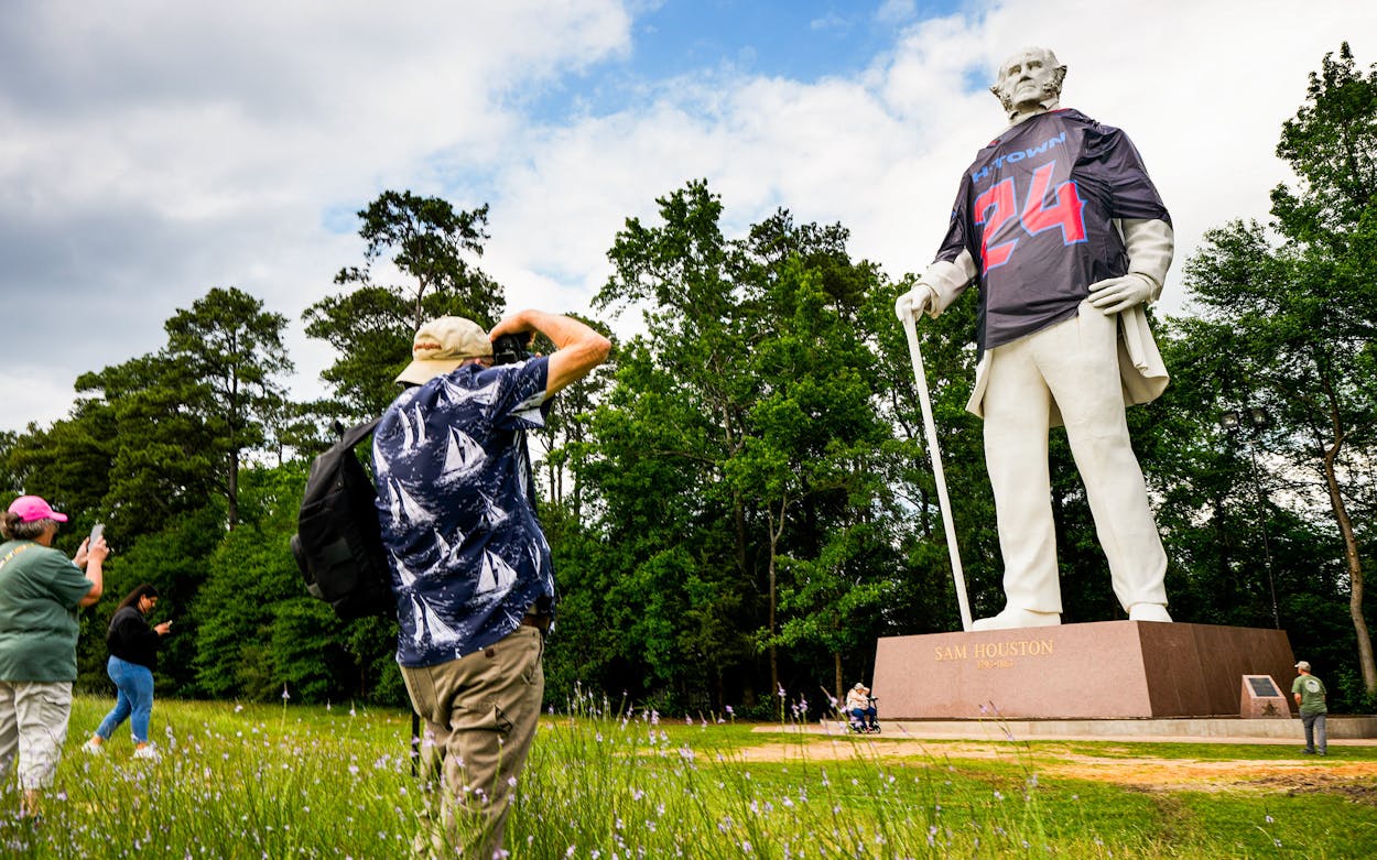 Onlookers stop to take photos of the Sam Houston statue wearing a Houston Texans jersey in Huntsville.