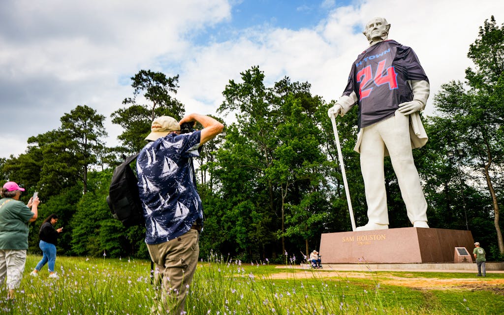 Onlookers stop to take photos of the Sam Houston statue wearing a Houston Texans jersey in Huntsville.
