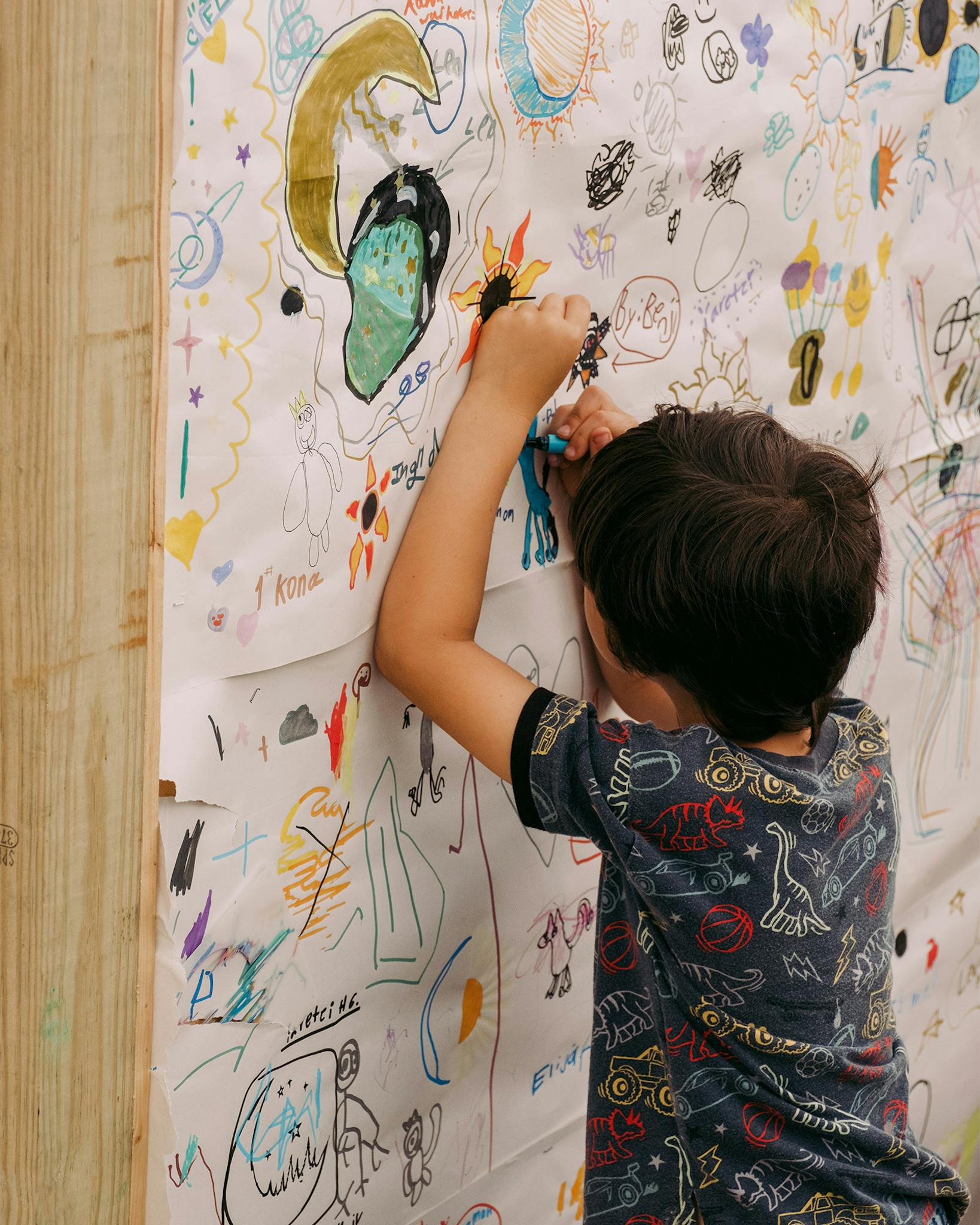 A child contributes his artwork to the community mural wall.