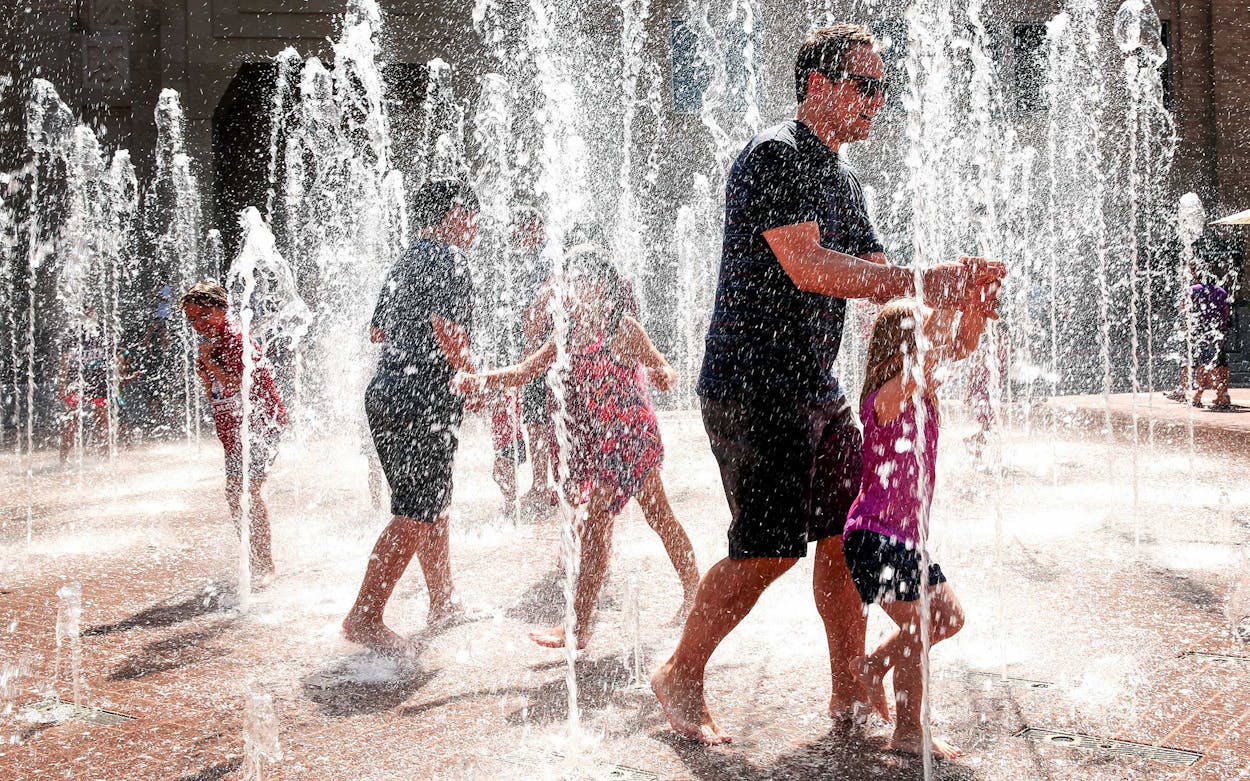 People cool off in the Sundance Square fountain in downtown Fort Worth on July 26, 2015.